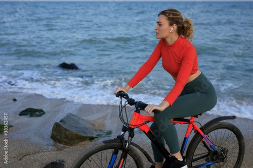 Young woman in orange t-shirt with bicycle on the sea beach
