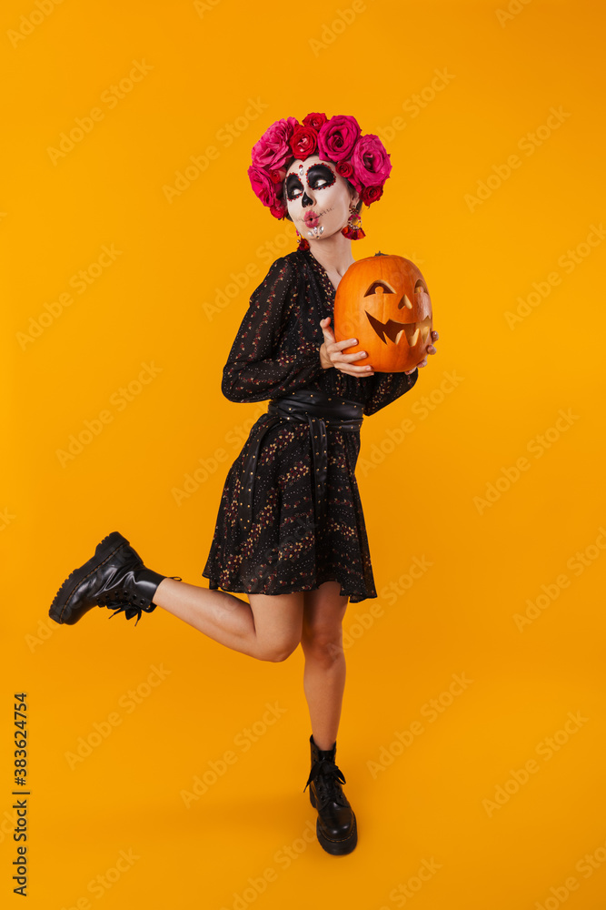 Amusing caucasian girl in halloween makeup posing with pumpkin Amusing caucasian girl in halloween makeup posing with pumpkin