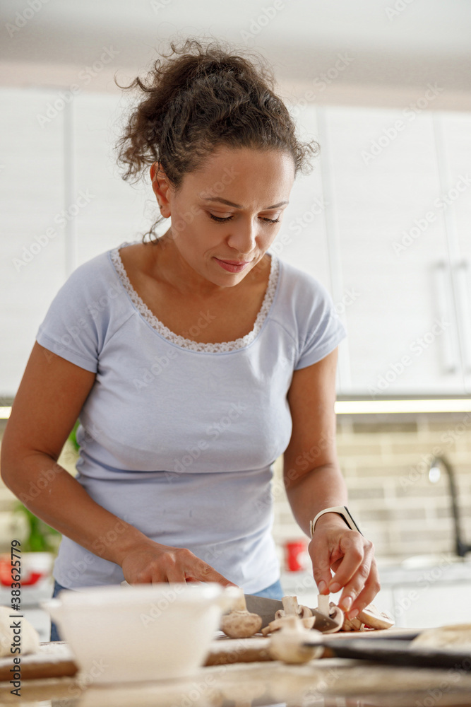 Beautiful smily handsome woman is preparing tasty fresh italian pizzawith vegetables at her kitchen at home Beautiful smily handsome woman is preparing tasty fresh italian pizzawith vegetables at her kitchen at home