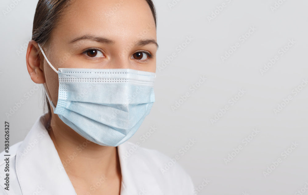 Close-up portrait of a woman covering her face with a medical blue mask, protecting against an outbreak of the coronavirus infectious disease COVID-19.