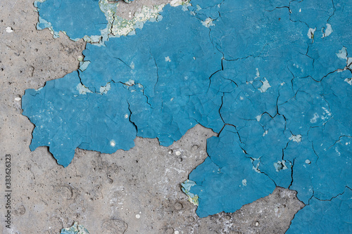 Blue peeling paint on the wall. Old concrete wall with cracked flaking paint. Weathered rough painted surface with patterns of cracks and peeling. High resolution texture for background and design. © Andrei Stepanov