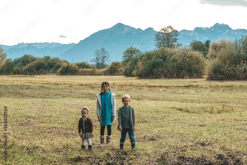 Kinder stehen auf dem Feld vor den Bergen