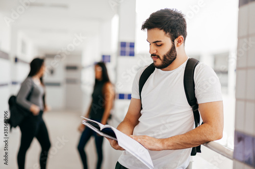 Brazilian university student reading book in the college corridor. photo