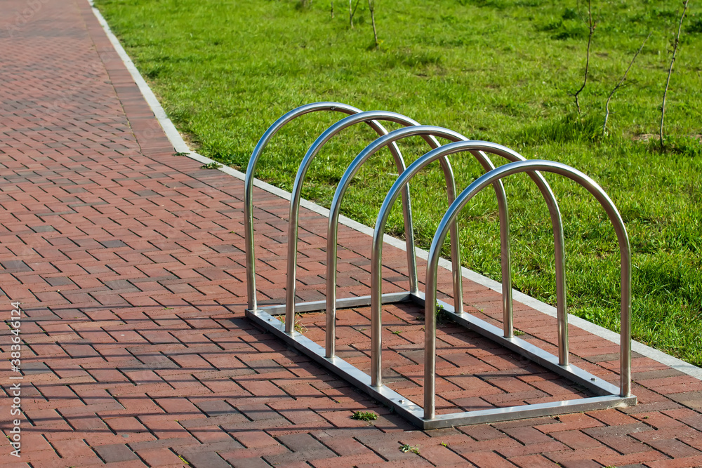 Modern Parking for bicycles made of stainless steel on the background of paving slabs Modern Parking for bicycles made of stainless steel on the background of paving slabs