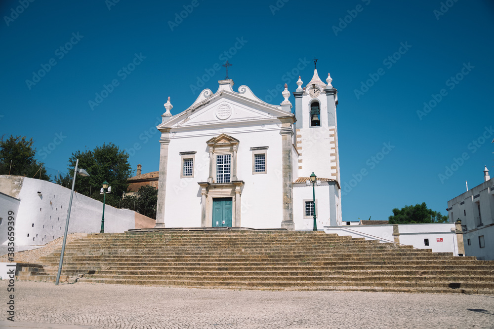 a large stone church to which stairs lead. church in portugal. church with a tower with bells