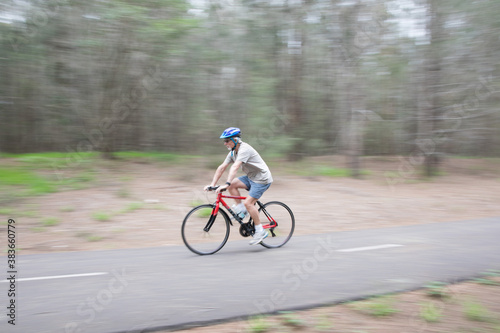 Active senior pensioner outdoors active exercising wearing a bike bicycle helmet overcast bit of rain bike path riding a bike keeping busy during self isolation healthy 