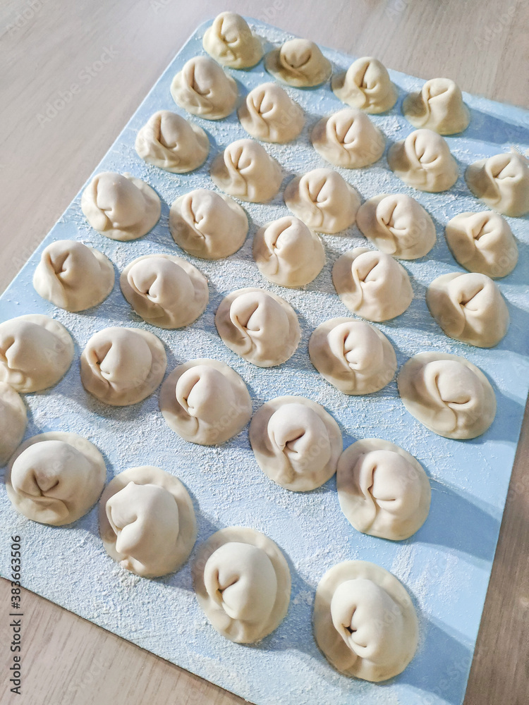 Raw homemade dumplings on a blue board. Molding dumplings. High quality photo