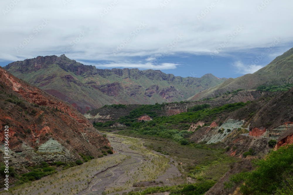 Explore the wild. View of the valley, forest, mountain flora, red sandstone and rocky hills under a cloudy sky. 