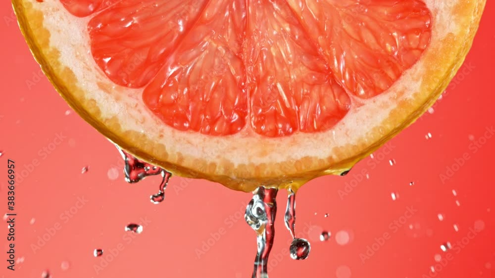 Super Slow Motion of Water Splash on Fresh Backlit Grapefruit Slice. Shot in 1000 fps.