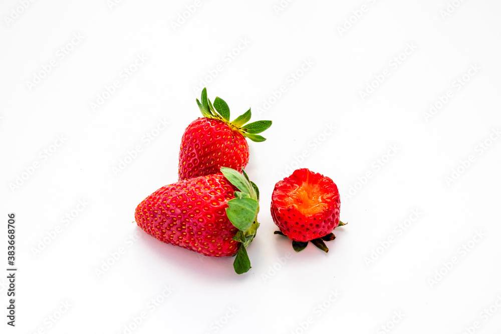 3 isolated strawberries on a white background. One berry has a bite taken from it.