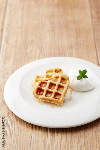 heart shaped waffles on a white plate, wooden table
