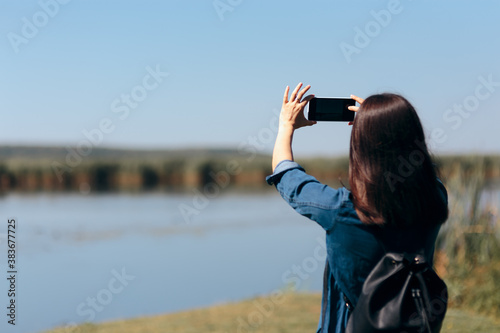 Woman Taking Vacation Photos of a Lake with her Smartphone 