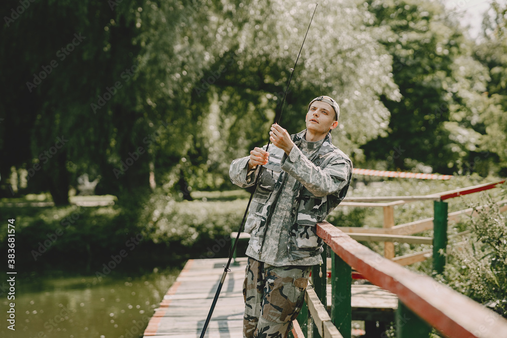 A man fishing on a lake. Guy in a uniform.