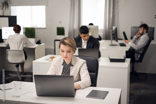 A young girl Manager in the office in a working dress code with a laptop communicates with a client of the company