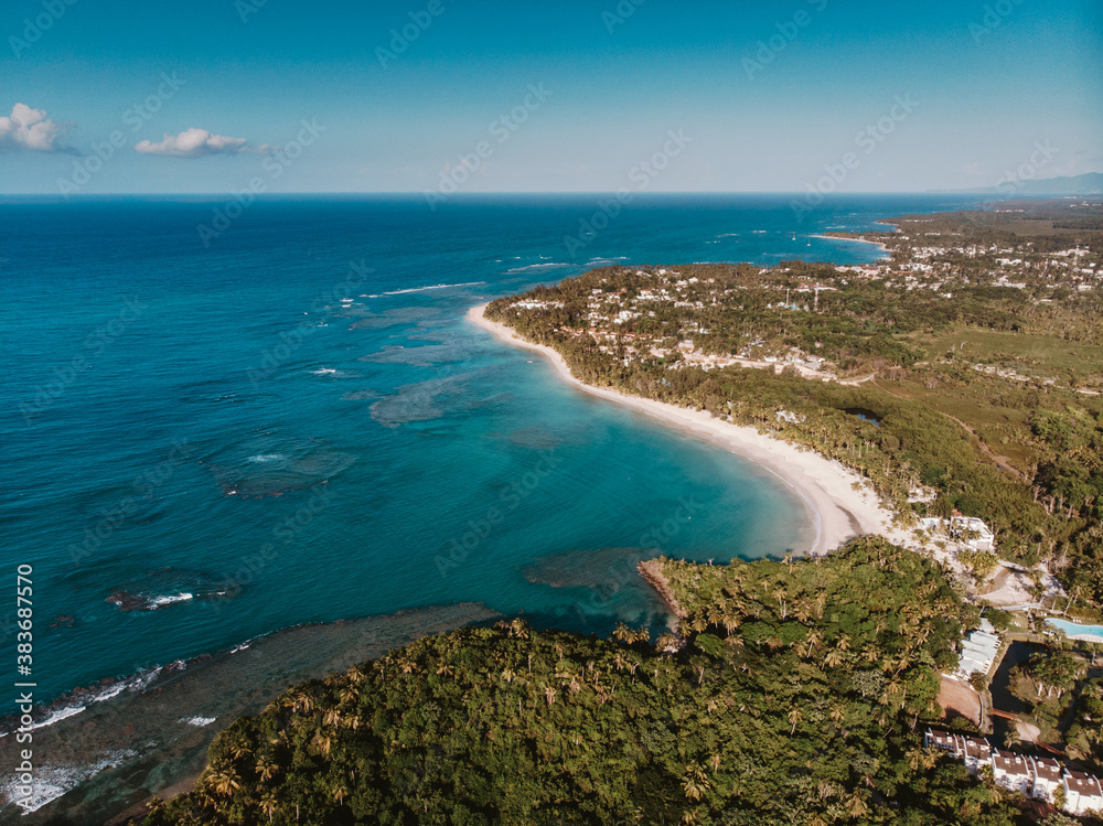 Aerial drone panoramic view of the paradise beach with sandy and rocky shore, palm trees and blue water of Atlantic Ocean, Las Terrenas, Samana, Dominican Republic