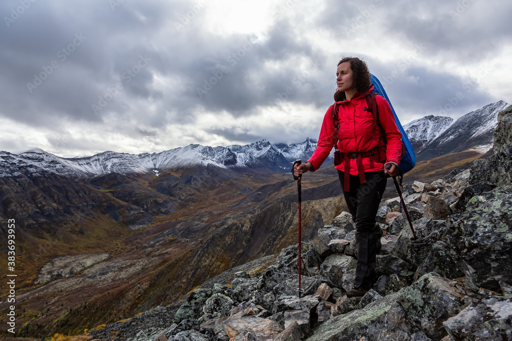 Girl Backpacking along Scenic Hiking Trail surrounded by Mountains in Canadian Nature. Taken in Tombstone Territorial Park, Yukon, Canada.
