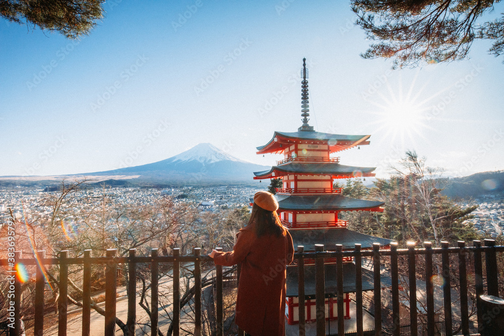 Pretty Girl standing Behind at Beautiful view of mountain Fuji and Chureito pagoda, Fujiyoshida, Japan. Backgound of Fuji Autumn leaves during sunset with clear blue sky.