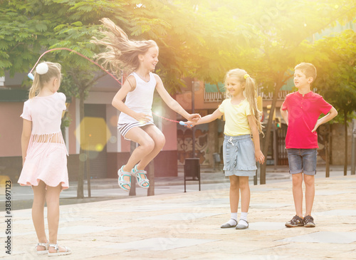 portrait of happy children skipping together with jumping rope on urban playground.