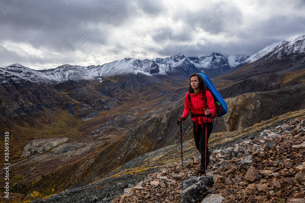 Girl Backpacking along Scenic Hiking Trail surrounded by Mountains in Canadian Nature. Taken in Tombstone Territorial Park, Yukon, Canada.