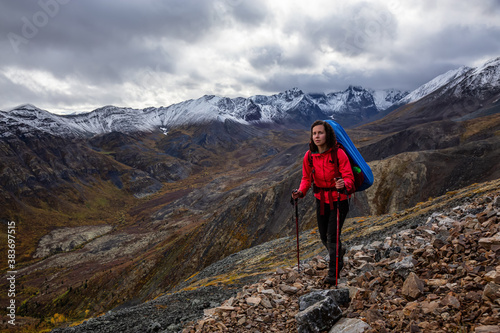 Girl Backpacking along Scenic Hiking Trail surrounded by Mountains in Canadian Nature. Taken in Tombstone Territorial Park  Yukon  Canada.