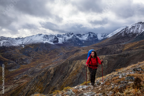 Girl Backpacking along Scenic Hiking Trail surrounded by Mountains in Canadian Nature. Taken in Tombstone Territorial Park, Yukon, Canada.