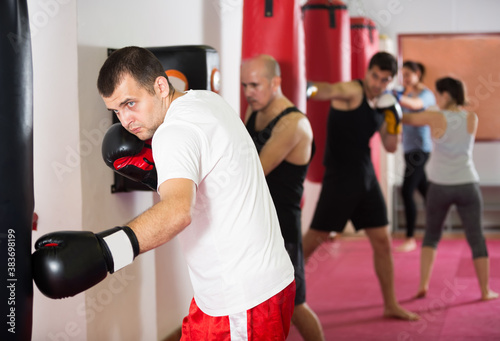 .Portrait of male beating boxing bag training in boxing gloves