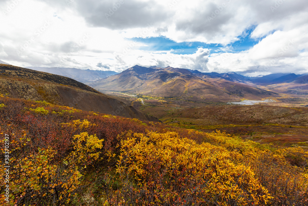 Scenic View of Road, Landscape and Mountains on a Colorful Fall Day in Canadian Nature. Taken in Tombstone Territorial Park, Yukon, Canada. Scenic View of Road, Landscape and Mountains on a Colorful Fall Day in Canadian Nature. Taken in Tombstone Territorial Park, Yukon, Canada.
