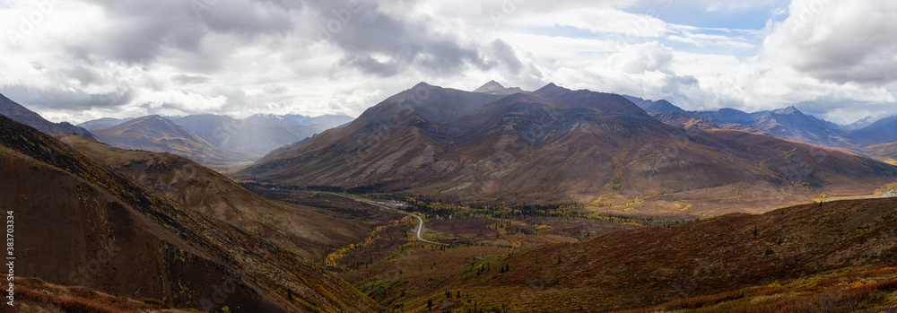 Panoramic View of Scenic Road from Above surrounded by Trees and Mountains during Fall in Canadian Nature. Aerial Shot. Taken in Tombstone Territorial Park, Yukon, Canada.