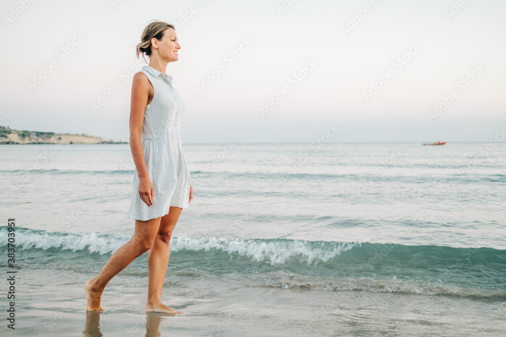 Young woman walking on the beach near the sea Young woman walking on the beach near the sea