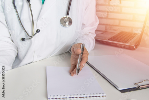 A female doctor talks to a patient, explains the concept of treatment, against the background of a laptop in the medical office