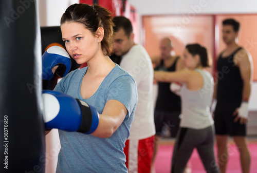 healthy sportswoman in the boxing hall practicing boxing punches with boxing bag during training