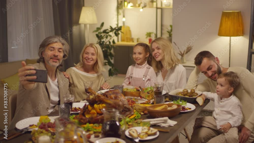 Big family having video call with their friends on smart phone while celebrating Thanksgiving day at home Big family having video call with their friends on smart phone while celebrating Thanksgiving day at home