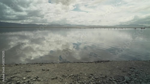 Shores of Chaka Salt Lake in China - Clouds reflected in Still Water with Tourists standing in the Distance photo