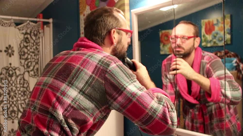 Man trimming his beard in the bathroom mirror. Man trimming his beard in the bathroom mirror.
