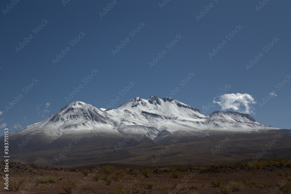 Snowy Andean volcano mountain close to northern chilean argentinean border in a shiny blue sky day.