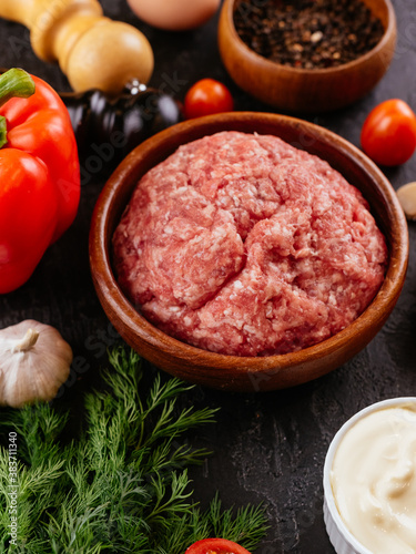 Canvas Print fresh raw minced pork in a wooden bowl with vegetables on the ba