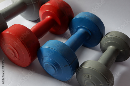 Various sizes and colors of barbells on a white background