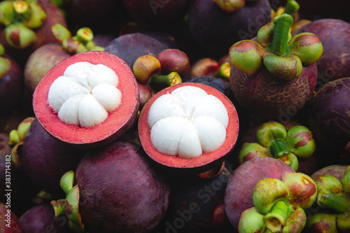 Fresh ripe mangosteen fruits and cross section showing the thick purple skin and white flesh.