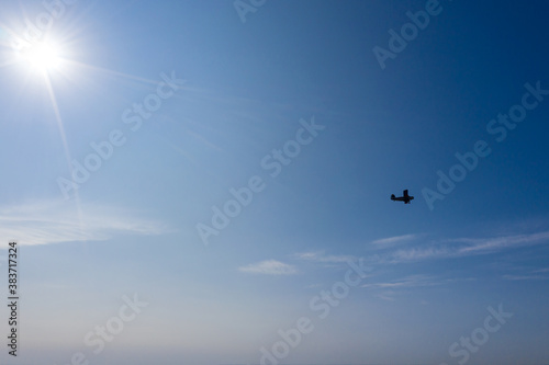 small airplane silhouette in flight against the backdrop of the clear blue sky. aerial photo