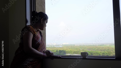 indian wife waitng for husbend on balconey while having tea photo