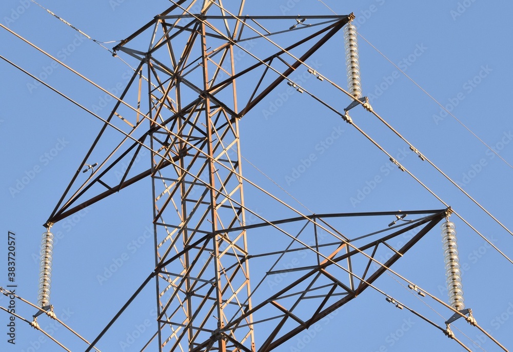 Power line with glass insulators and wires with transmission tower. Blue sky in background. Power line with glass insulators and wires with transmission tower. Blue sky in background.