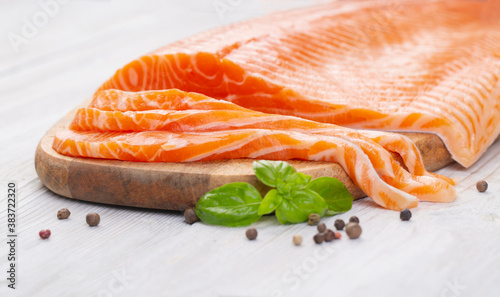 Raw fresh salmon fillet cut into slices and piece on wooden board