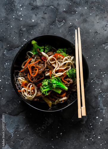 Asian udon noodles with beef and vegetables - delicious lunch on a dark background, top view