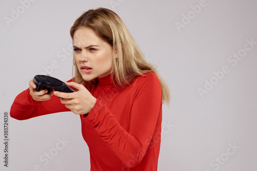 Woman with gamepad in hands playing games emotions lifestyle leisure red shirt light background