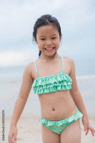 Little  girl playing on the beach on summer holidays. Children in nature with beautiful sea, sand and blue sky. Happy kids on vacations at seaside running in the water. .