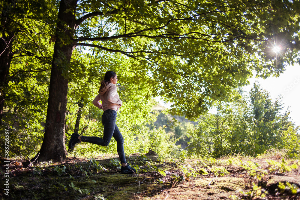 Young woman wearing yoga pants meditating in the woods on a sunny