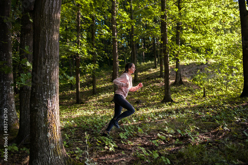 Young woman wearing yoga pants meditating in the woods on a sunny morning. © xpabli