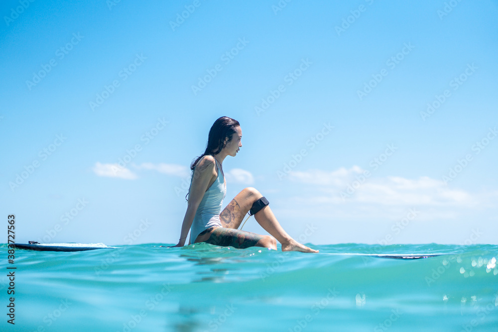 Portrait of surfer girl on surf board in blue ocean