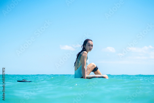 Portrait of surfer girl on surf board in blue ocean © Lila Koan
