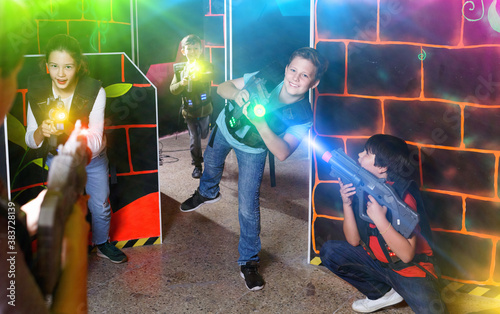 Group of happy pleasant teenagers with laser guns having fun on dark lasertag arena © JackF